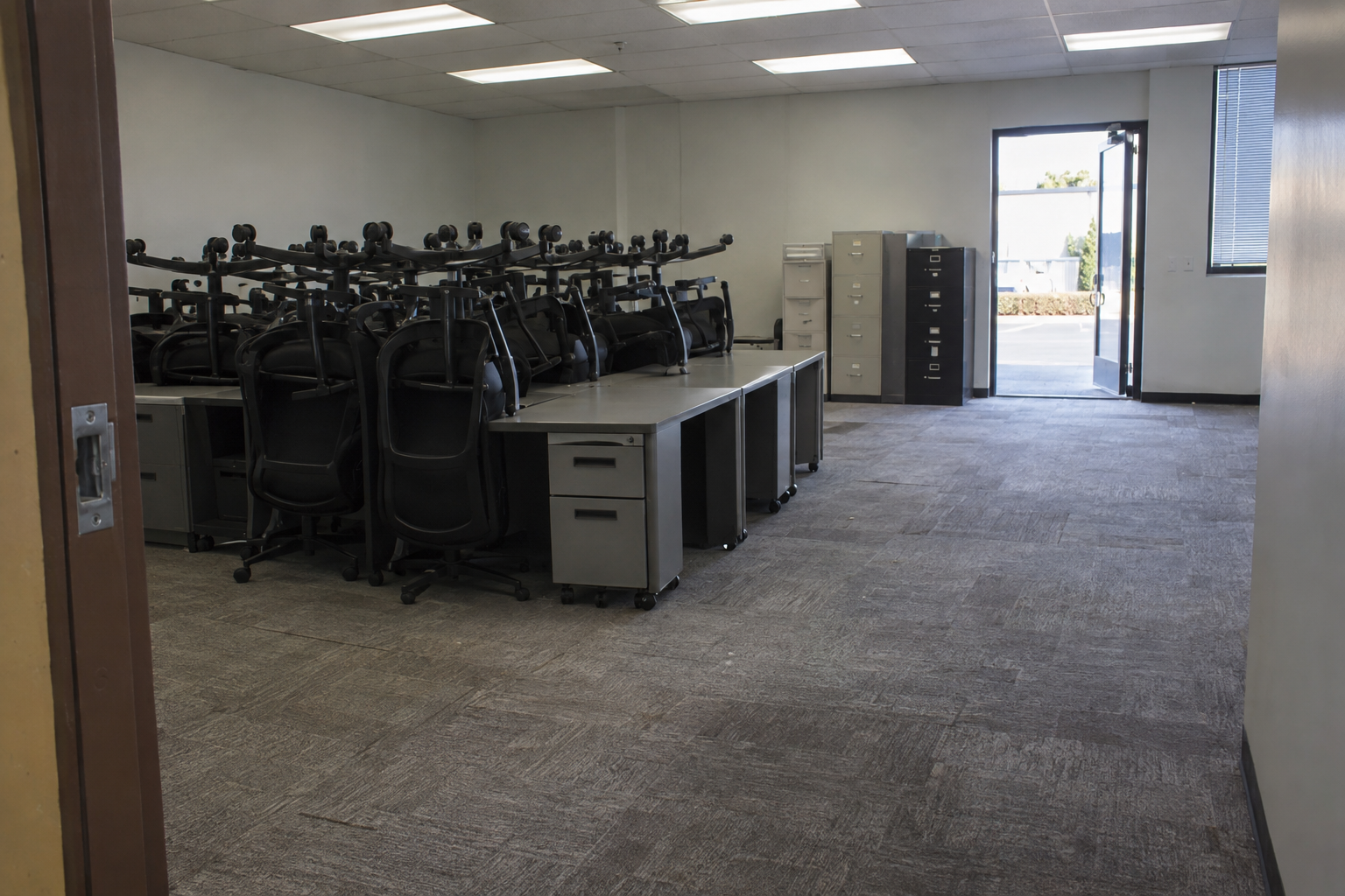 Cleared office suite with desks pushed together and chairs stacked